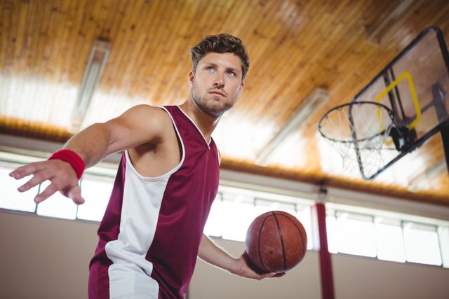 Man practicing basketball in an indoor court, showcasing determination and focus. Ideal for use in sports-related content, fitness promotions, athletic training programs, and motivational materials.