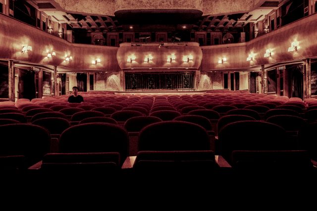Lonely Person Sitting in an Empty Theater Hall with Rows of Seats - Download Free Stock Photos Pikwizard.com
