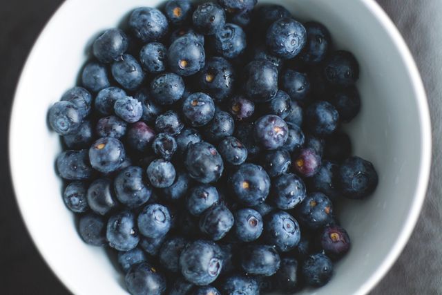 Close-up of a bowl filled with ripe, fresh blueberries. The image can be used in articles related to healthy eating, fruit nutrients, recipes, or breakfast ideas. Suitable for websites, blogs, promotional material in health and wellness, or food and beverage industries.