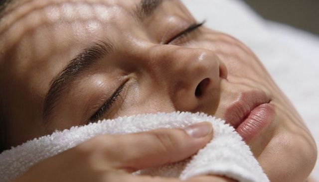 Relaxing spa facial with towel compression and patterned light shadows closeup
