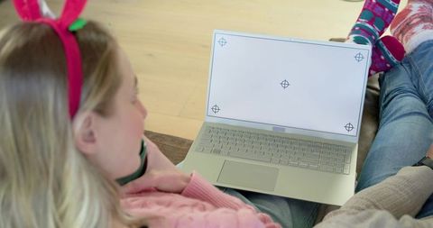 Couple relaxing on sofa sharing laptop, cozy casual home scene with patterned socks