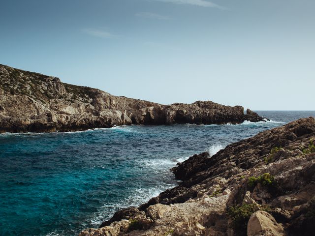 This image shows a rugged coastal landscape with rocky cliffs and a clear blue sea under a sunny sky. Waves are gently hitting the shore, making it a perfect depiction of natural beauty. Ideal for use in travel-related promotions, nature blogs, environmental articles, or inspirational postcards showcasing stunning coastal scenery.