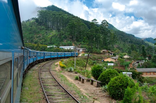 Vibrant blue train curving through lush green hills and serene countryside scenery. Suited for travel and tourism themes, emphasizing relaxation, escape, and scenic beauty.