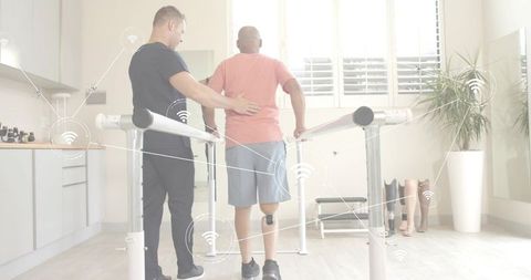 Therapist guiding patient walking on parallel bars with wearable sensors and prosthetics