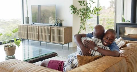 Joyful Embrace Between African American Father and Son in Modern Living Room