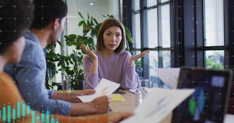 Woman Leading Team Discussion Over Charts and Laptop in Sunlit Modern Conference Room
