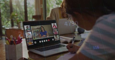 Girl attending virtual classroom on laptop while studying at sunlit home desk