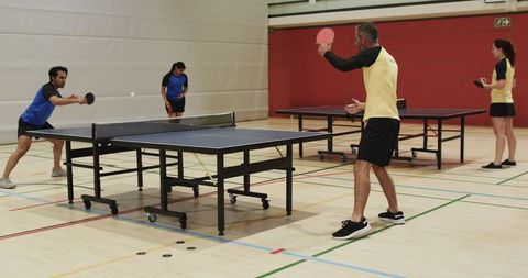 Intense table tennis game in indoor sports facility with diverse players