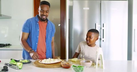 Father and Son Preparing Homemade Pizza in Modern Kitchen