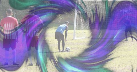 Soccer player preparing penalty kick near goal with purple abstract swirl overlay on grass