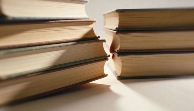 Vintage hardcover book stacks showing yellowed pages and paper texture, macro composition