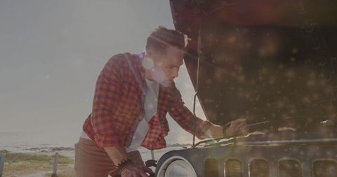 Mechanic checking car engine by coastal roadside