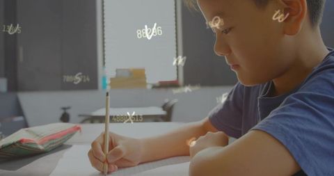 Focused schoolboy writing math notes with glowing number overlay in bright sunny classroom