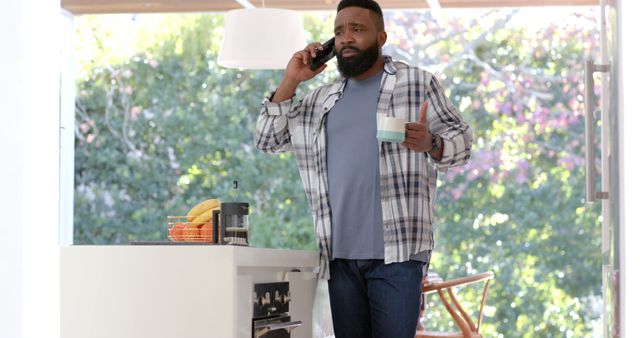 Man Drinking Coffee While Talking on Phone in Modern Kitchen - Download Free Stock Images Pikwizard.com