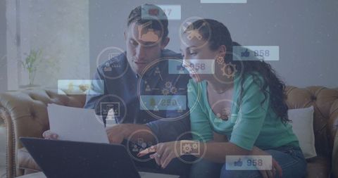 Couple analyzing report on couch with interactive icons overlay