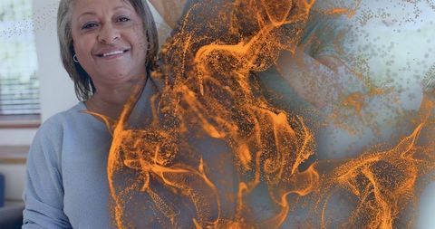 Senior woman smiling in cozy living room with orange particle overlay and copy space