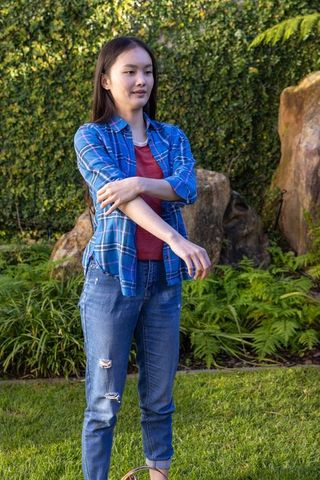 Woman adjusting sleeve outdoors in garden background