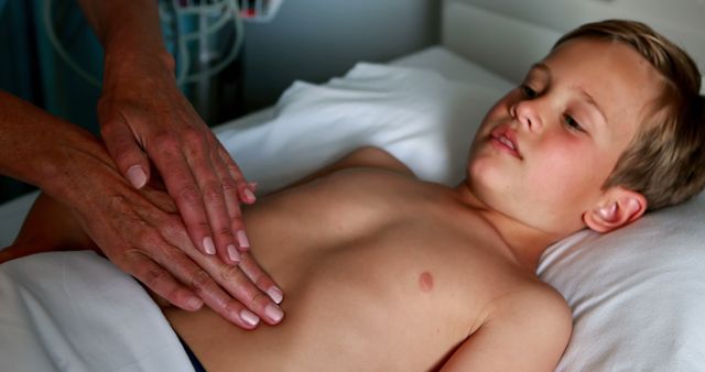 A young boy on a hospital bed receiving a medical examination from a healthcare professional. This can be used to represent pediatric care, medical check-ups, healthcare services, or educational materials about child health.