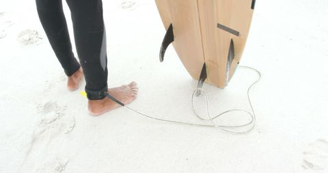 Surfer with board and leash on sandy beach ready for action