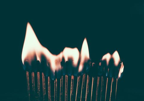 Row of Burning Matchsticks Creating Dramatic Flame Wave on Dark Background