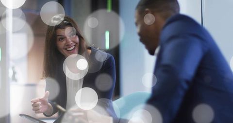 Smiling businesswoman gesturing with tablet during collaborative meeting in modern office
