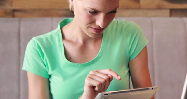 Young woman using tablet in casual green shirt indoors - Download Free Stock Images Pikwizard.com