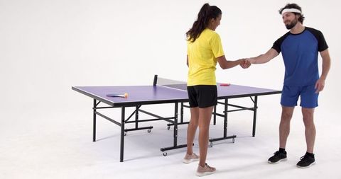Friends playing table tennis shaking hands in modern studio
