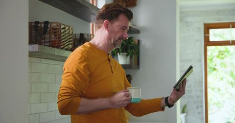 Middle-aged man using tablet in modern kitchen