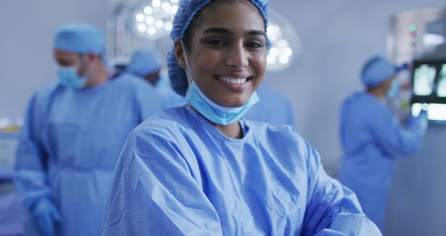 Female surgeon wearing surgical scrubs and mask, smiling confidently in operating room. Ideal for illustrating themes of healthcare, medical professionalism, teamwork, hospitals, and surgical procedures.