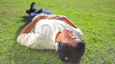 Relaxed Man Enjoying Music Lying on Grass
