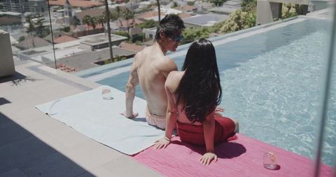 Sunlit rooftop infinity pool couple relaxing: urban romance, luxury terrace escape