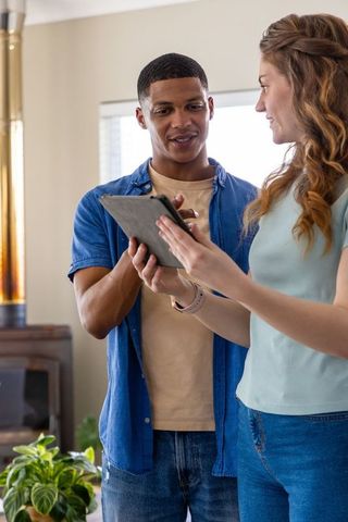 Young african american man and woman using tablet in cozy living room with smartwatch