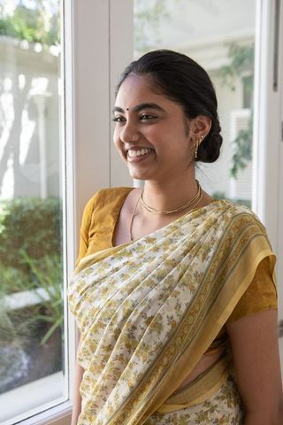 Happy Indian Woman in Yellow Sari Smiling by Sunlit Window