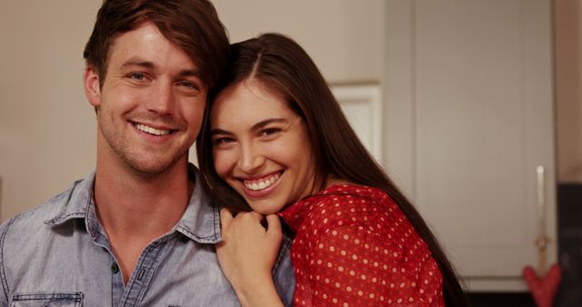 Couple smiling and embracing indoors. Perfect for advertisements, relationship blogs, family websites, and lifestyle magazines emphasizing love and happiness in a cozy home environment.