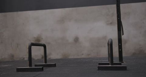Pair of metal parallettes on gym floor near squat rack