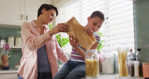 Mother and Daughter Unpacking Groceries Together in Kitchen