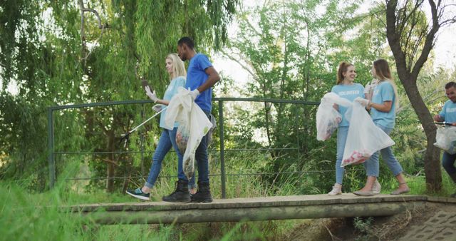 A multi-ethnic group of conservation volunteers cleaning up a river on a sunny day in the countryside, walking on a bridge. Ecology and social responsibility in a rural environment.
