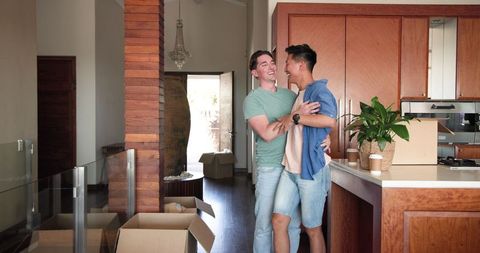 Happy diverse couple dancing in new home kitchen