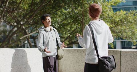 Friends chatting on urban terrace with backpacks & headphones, casual campus conversation