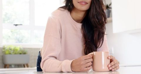 Mid adult woman relaxing in cozy kitchen with warm beverage