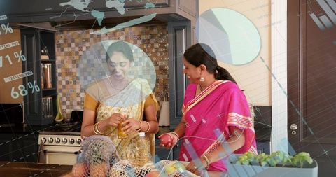 Women in saris preparing produce at modern kitchen island using mesh bags and fresh fruit