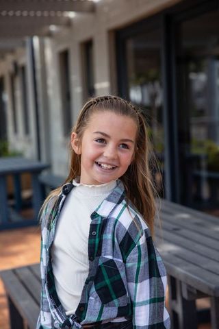Cheerful Girl Smiling Joyfully Outdoors by Wooden Patio