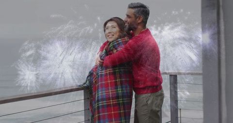 Couple embracing on waterfront deck under spectacular fireworks