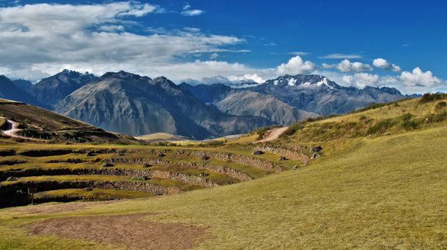 Picturesque view capturing terraced fields set against the backdrop of the majestic Andean mountains under a clear blue sky. Ideal for travel and tourism promotions, nature blog visuals, scenic calendars, or agricultural study materials.
