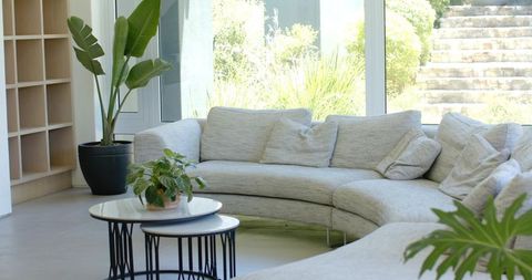 Curved gray sectional sofa framing sunlit modern living area with nested coffee tables