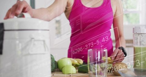 Preparing green smoothie while chopping cucumber and apples on kitchen counter