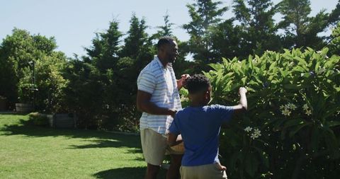 African american father and son harvesting flowers in sunny backyard garden bonding via gardening