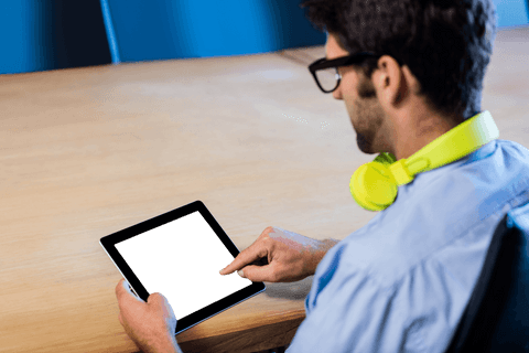 Man wearing headphones using transparent digital tablet at work desk