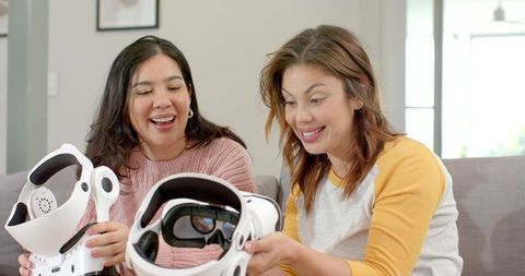 Friends testing wellness VR helmets on couch, laughing and sharing immersive VR experience