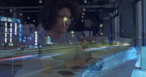 Woman Using Laptop in Cafe with Night City Traffic Blending